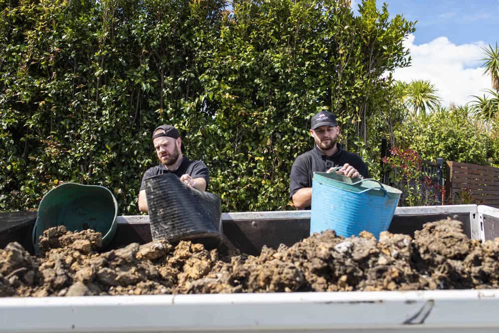 Team filling up trailer with soil